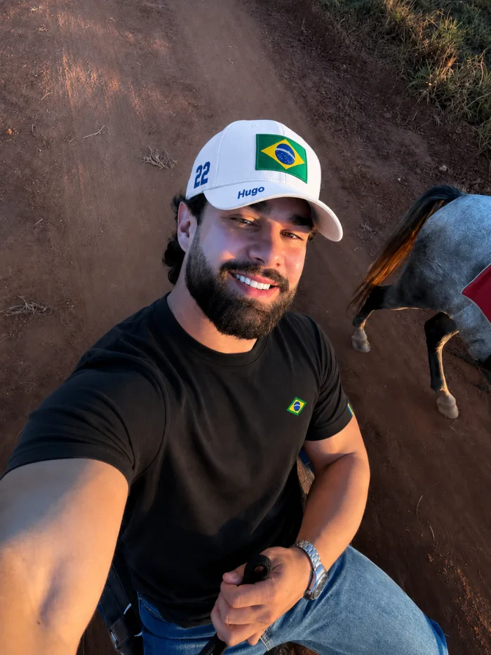 Cliente sorrindo com boné branco do Brasil e nome bordado, ao ar livre